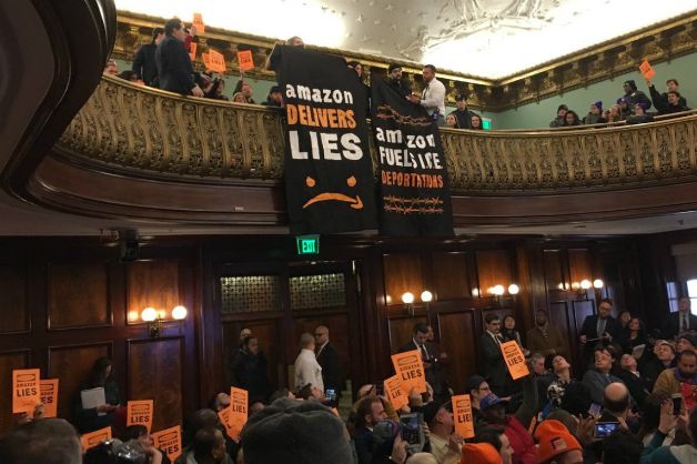 Protesters drop a banner during the City Council's hearing on Amazon's plan to build a massive campus in Long Island City on Wednesday